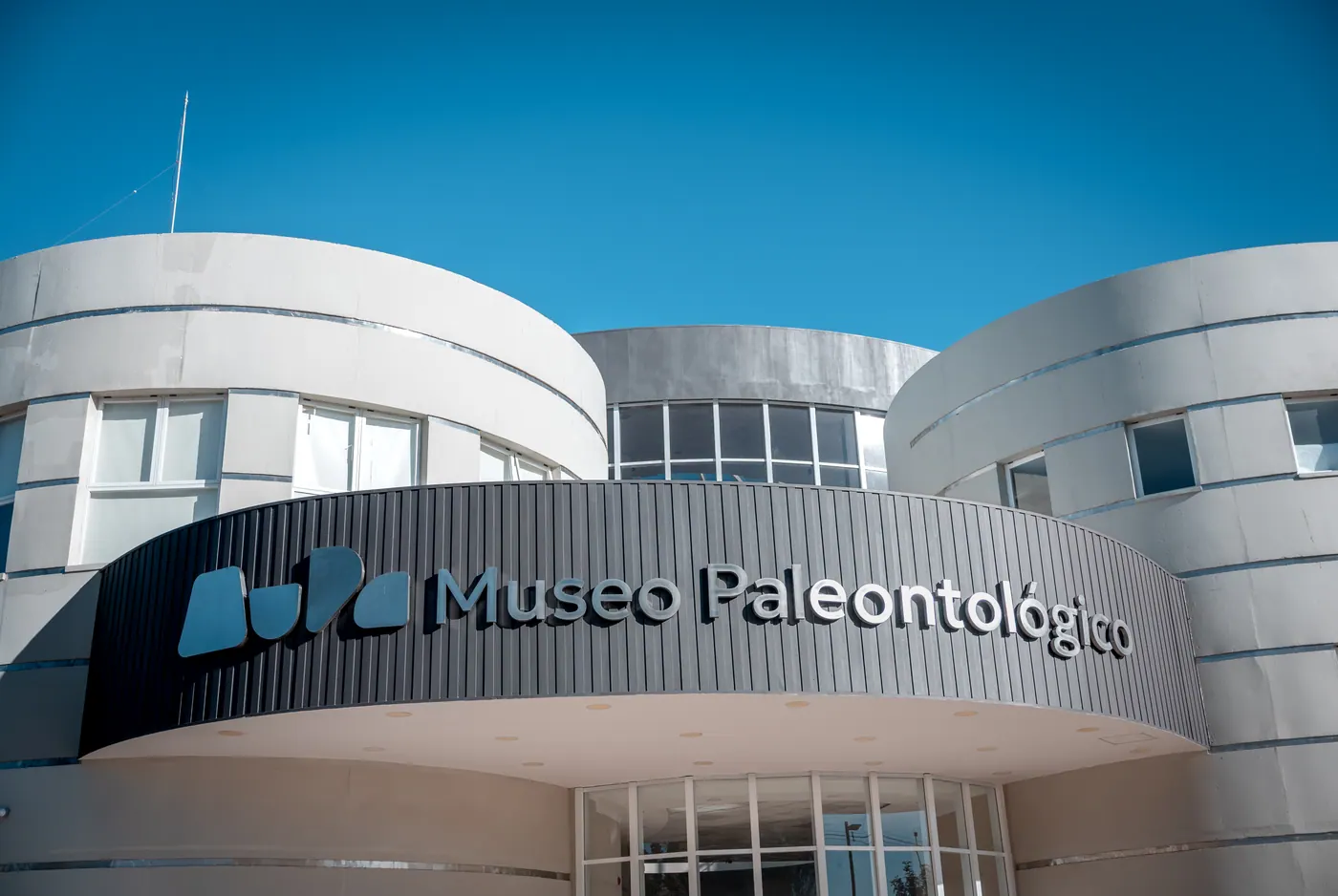 Cartel "Museo Paleontológico" con la marca MuPa sobre la entrada del edificio, contra el cielo