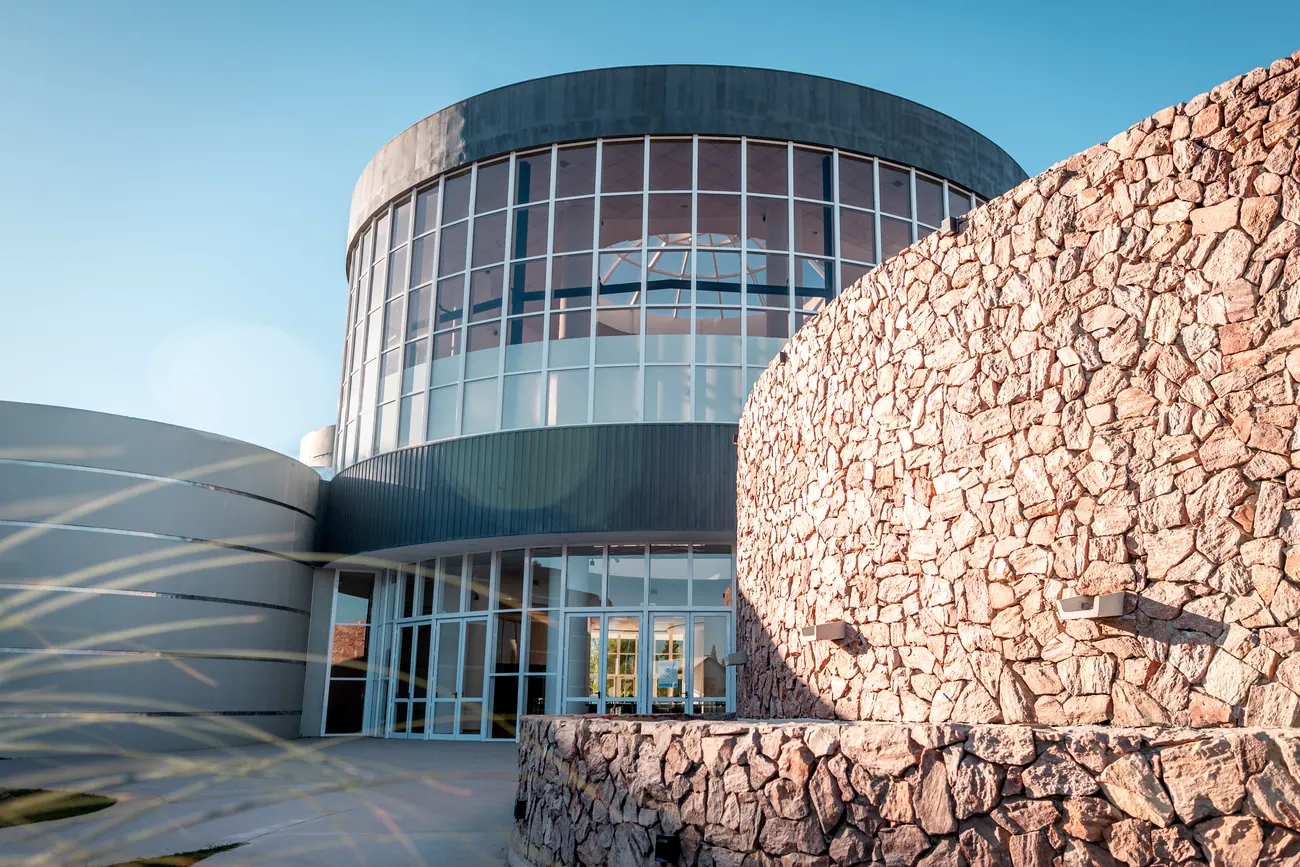 Entrada del museo de día, con el muro de piedra y la cúpula vidriada
